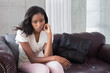 © wavebreak3 - African American woman sitting on sofa in living room with grey and black cushions leaning forward
