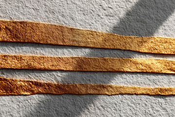Poster - Golden textured lines on rough gray surface with soft shadows creating minimalist abstract composition
