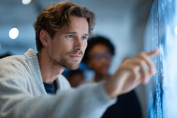 Poster - Focused man interacts with a screen display, analyzing data with a colleague. Represents technology, research, progress, future, and collaboration.