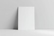 © Kamil - Minimalist studio mockup of a blank white A4 flyer standing upright against a light gray wall, resting on a clean flat surface