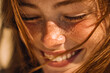 © Daria - Close-up of a joyful young girl with freckles enjoying a sunny moment
