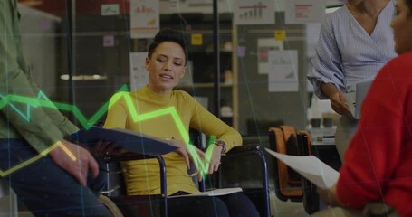 Poster - Wheelchair user gesturing as man moving blue folder animating line graph trends in business meeting