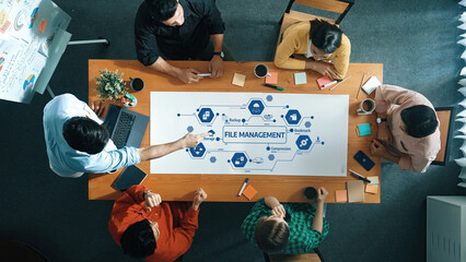 Poster - A diverse team collaborates in a file management strategy session at a modern office. They utilize technology and visual aids, enhancing teamwork and productivity. Amity