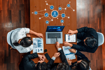 Poster - A diverse group of professionals gathers around a table during a meeting. They analyze business charts and graphs displayed on the laptop, discussing strategies and insights. Amity