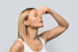 © Prostock-studio - Nosebleeds concept. Middle aged blonde woman with closed eyes touching nose, suffering from bleeding or dry nose, grey studio backgroundm side view, closeup shot