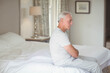© WavebreakMediaMicro - Senior man wearing striped pajamas sitting on bed edge with crossed arms bowed head in bedroom