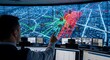 © Zaldy - A city traffic manager monitors and interacts with a large interactive map displaying real-time traffic flow and incidents.