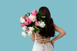 © Pixel-Shot - Young woman with bouquet of peony flowers on blue background, back view