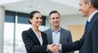 © ngamaz - Business handshake, three people, smiling, modern office setting.