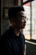 © Huyn - Man in glasses looks thoughtfully out the window, reflecting on life in a quiet urban space during the late afternoon