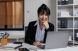 © David - An attractive young Asian woman sitting at a laptop in a workplace office.