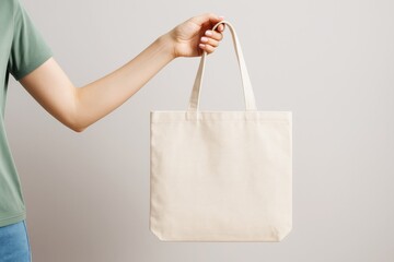 Poster - Hand holding blank beige canvas tote bag with clean background for branding or promotional design mockup concept.