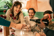 © Lomb - Group of diverse friends laughing and celebrating a festive Christmas party. Happy multi-ethnic people sharing champagne and a joyful moment during a holiday dinner at home.