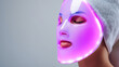 © dinatychynska - LED light therapy mask for facial skincare treatment. Purple phototherapy device for anti-aging, acne treatment and skin rejuvenation. Modern beauty technology concept.