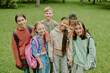 © AnnaStills - Group of diverse children standing together in park smiling at camera, multiethnic boys and girls with backpacks posing outdoors during school outing or educational activity