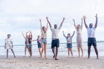 group of diverse friends and family gathering on the beach doing hands up together in the evening su