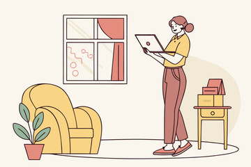 Poster - Young woman using a laptop while standing in a cozy living room with a bright window and a comfortable armchair