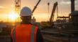© Karmiyem - Construction worker overlooking a large scale project at sunset, feeling proud of his team's hard work and dedication to completing this massive undertaking on time.