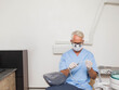 © WavebreakMediaMicro - Senior male dentist wearing scrubs and gloves inspecting suction hose at dental chair in exam room