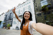 © Westend61 - Happy tourist taking selfie in front of colorful urban houses outdoors