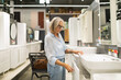 © Ivan Traimak - Woman selecting bathroom furniture in a home goods store while enjoying the shopping experience and examining various options