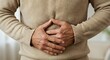 © Helen - Man clutching stomach in pain. Abdominal discomfort and digestive health issue. Healthcare and medical concept for wellness.