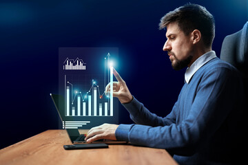 Poster - Professional man analyzing data trends and graphs on a laptop in a modern workspace at night