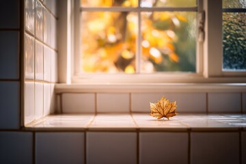 Poster - Autumn leaf resting on a windowsill with warm light illuminating a cozy kitchen setting