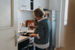 © qunica.com - A senior woman is preparing a meal in her kitchen, showing a comforting scene with an emphasis on home-cooked traditions and a warm domestic atmosphere.