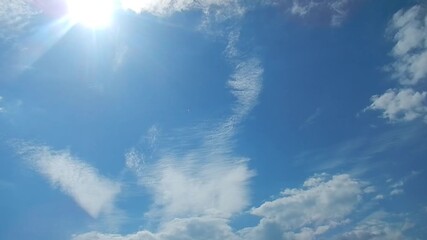 Poster - Natural sunny sky background with sun rays and small white clouds. Topics: sunny weather, holidays, warm climate, sun energy, summer, cloudscape, meteorology, nature