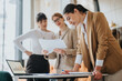 © qunica.com - Businesswomen in a workspace reviewing documents and laptop data, collaborating on strategies and solutions to enhance productivity and teamwork.