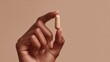 © Oleksandr - A hand holding a nutritional supplement. Close-up of a light brown capsule. Healthcare, wellness, and medical concept.