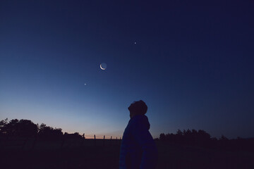 Wall Mural - silhouette of a man observing moon, milky way stars, planets and other celestial objects from a dark