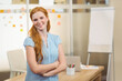 © WavebreakMediaMicro - Red-haired woman crossing arms at desk in office with sticky notes and flipchart