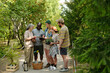 © pressmaster - Group of multiethnic adults and teenagers standing outdoors sharing gardening tools and potted plants, smiling and interacting together on park pathway surrounded by greenery