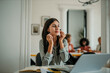 © La Famiglia - Businesswoman putting on wireless earphones at her desk in the office