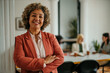 © La Famiglia - Smiling senior businesswoman posing with crossed arms in modern office