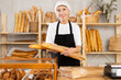 © JackF - Kind old female marketer offering baguettes in pulp bag in bakehouse