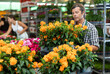 © JackF - Adult male salesman in uniform holding pot of crossandra in flower shop