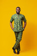 © Prostock-studio - Handsome black man in traditional african green clothes posing over yellow studio background