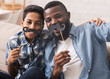 © Prostock-studio - Black father and his preteen son taking selfie, holding fake moustache on sticks and smiling at camera, having fun at home