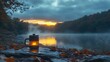 © diyanskb1018 - Atmospheric outdoor camping scene featuring illuminated coffee maker and scenic lakeside sunrise