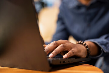 Poster - African american woman multitasking on a laptop in her stylish loft, fully connected to the internet while managing her freelance tasks and remote responsibilities. Browsing web at her home.