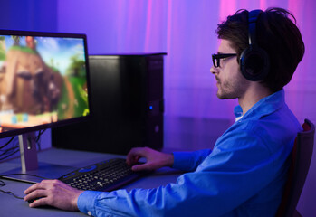 Online Gaming. Gamer Guy Playing Games Sitting At Desktop PC At Home At Night. Selective Focus, Low Light