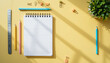 © Chookeit - Top view of creative workspace with blank grid notebook, colorful pencils, ruler, clips, and plant on bright yellow background with sunlight shadows, ideal for design or study concepts