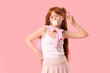 © Pixel-Shot - Cute ginger teenage girl blowing bubble gum and showing victory gesture on pink background