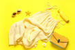 © Pixel-Shot - Female summer dress with sunglasses, sunscreen and handbag on yellow background