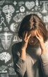 © pisan thailand - A woman holds her head in distress, surrounded by blurred medical and scientific symbols on a blackboard.