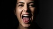 © adobesantren - Close-up portrait of a young woman with dark hair, mouth wide open, tongue visible, expressing joy or excitement against a dark background.