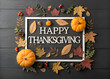 © sudangsho94 - happy thanksgiving day text in square shape frame and pumpkins and leaves on black wooden background